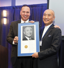 Tom Watanabe and President Ron Liebowitz together hold a framed plaque awarded to Watanabe